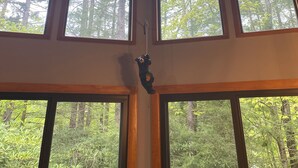 A room with a sloped ceiling, a ceiling fan, and multiple windows offering a view of a forest. - charming chalet in the Lake Naomi community (Pocono Pines)