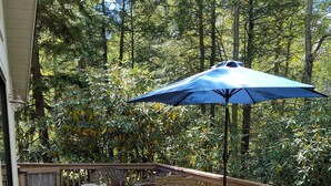 A wooden deck with a fire pit, outdoor furniture, and a large blue umbrella. - charming chalet in the Lake Naomi community (Pocono Pines)