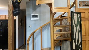 A wooden spiral staircase with a bear decoration, a sign indicating the house is on the market, and a tree-patterned screen. - charming chalet in the Lake Naomi community (Pocono Pines)