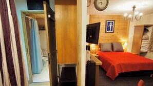 Una camera con un letto, una TV, una sveglia e una parete in legno.