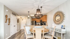 A kitchen with wooden cabinets, a chandelier, and a dining table with chairs.