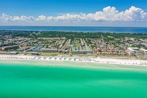 Luftaufnahme einer Küstenstadt mit Strand, Wohnhäusern und einem großen Hotelkomplex.