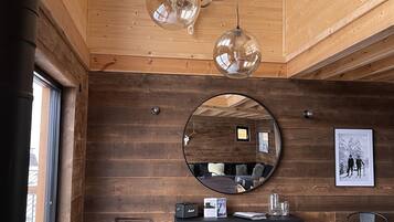 A modern interior with a wooden ceiling, a dining area with a large table and chairs, a round mirror, and a framed picture on the wall.