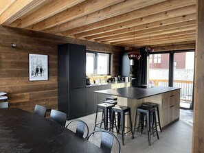 Una cocina moderna con una isla central, taburetes de bar y una mesa de comedor.