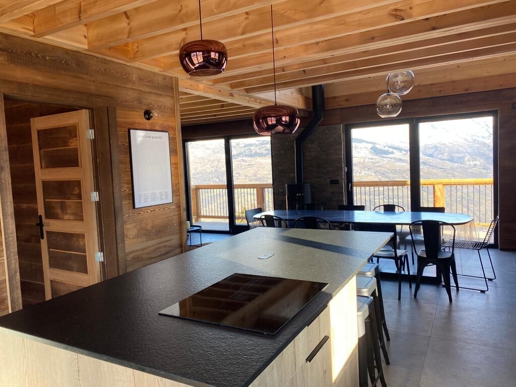 Una cocina moderna con una isla grande, techo de madera y ventanas amplias con vista a la montaña.