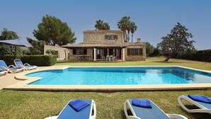 A swimming pool with lounge chairs and a stone building with a patio in the background. - COLLET VELL. Lovely stone-clad villa with large garden (Pollensa)