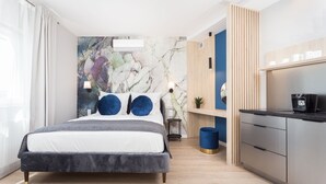 A modern bedroom with a bed, bedside lamps, a marble wall, a small table, and a kitchen area with a coffee machine. - Studio with sunny terrace with Wawel Castle View - near Main Square  (Kraków)