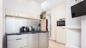 A modern kitchen with a built-in oven, a coffee machine, and a flat-screen TV mounted on the wall. - Studio with sunny terrace with Wawel Castle View - near Main Square  (Kraków)