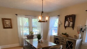 Un coin repas avec une table en bois, deux chaises, un banc et un tapis à motifs.
