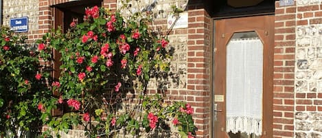 A brick building with a wooden door and a window. There is a sign above the door and a sign on the wall.