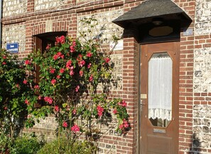 A brick building with a wooden door and a window. There is a sign above the door and a sign on the wall.