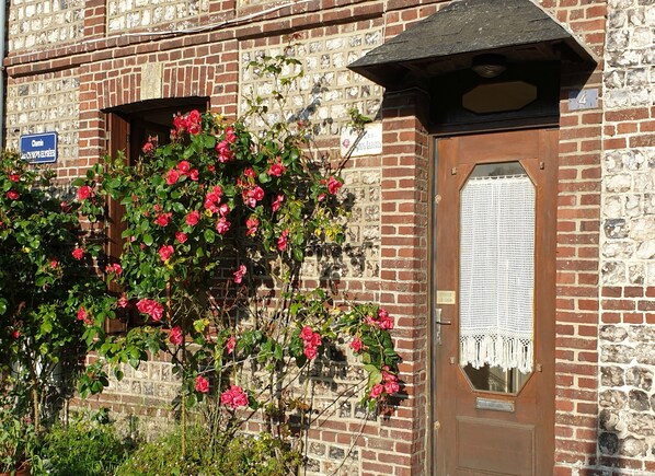 A brick building with a wooden door and a window. There is a sign above the door and a sign on the wall.