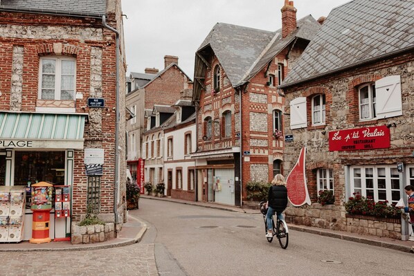 A street with buildings, a bicycle, and a person riding the bike.