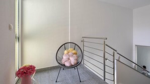 Una poltrona con cuscini, un vaso con fiori e una ringhiera metallica su una scala.