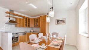 Una cucina moderna con mobili in legno, forno integrato e zona pranzo apparecchiata per un pasto.