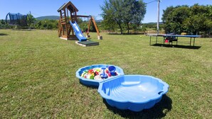 Un'area giochi con uno scivolo, altalene e un tavolo da ping pong.