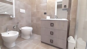 A bathroom with a toilet, bidet, and a vanity with drawers. - Suite Central Station Milano (Milano)