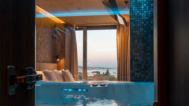 Ein moderner Spa-Bereich mit Whirlpool, Holzverkleidung und Blick auf die Stadt.