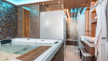 Relax in a spacious bathroom with a large hot tub and glass-enclosed shower area.