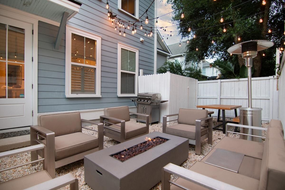 An outdoor patio with a fire pit, seating area, and string lights.