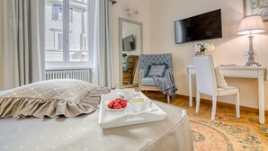 A hotel room with a bed, a desk, a chair, a TV, and a window with curtains. - Andromeda Luxury Apartment in Colosseum (Roma)