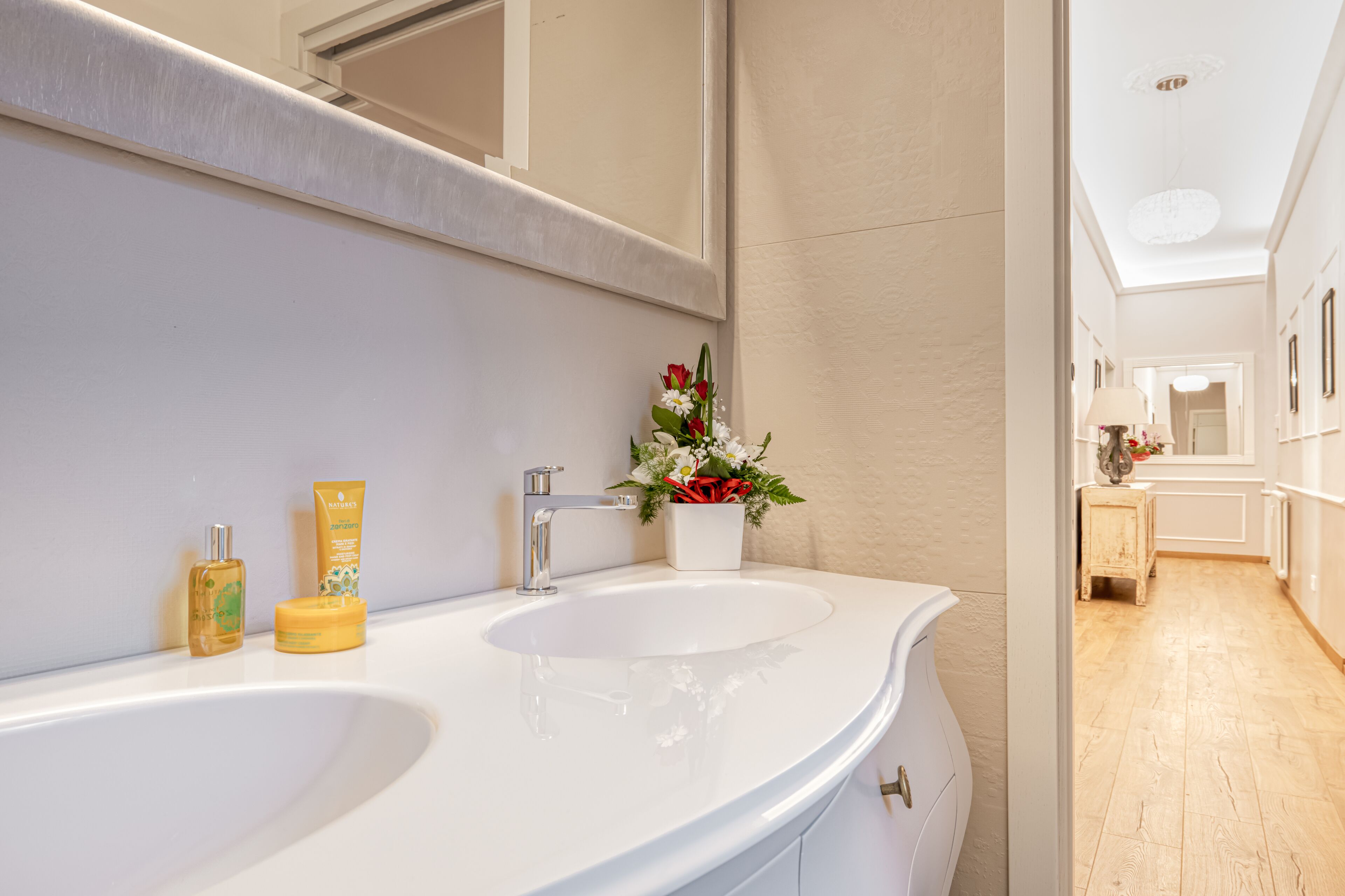 Une salle de bain moderne avec deux lavabos, un grand miroir et une petite plante en pot.