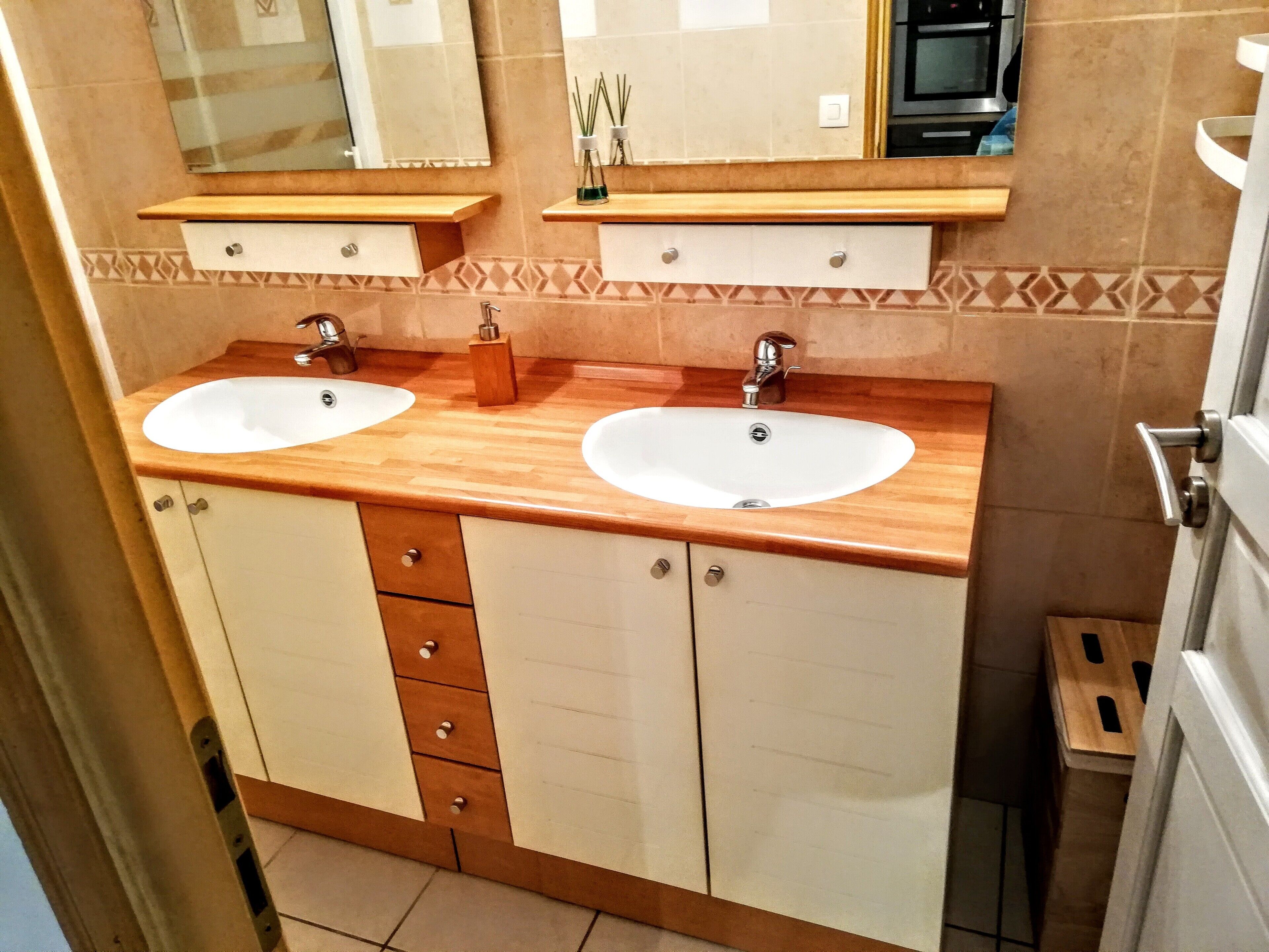 Un baño con dos lavamanos, tocador de madera y un espejo.