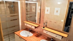 Baño con dos lavamanos, ducha y un espejo grande.