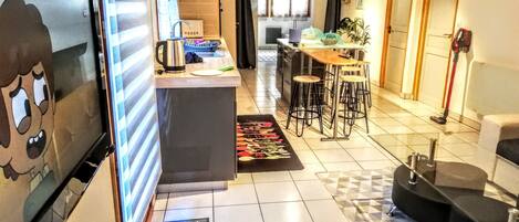 Een compacte keuken met een koelkast, een koffiezetapparaat en een kleine eethoek met krukken.