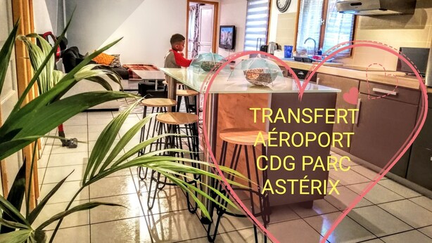 Una cocina con una isla central, taburetes de bar y una persona al fondo.