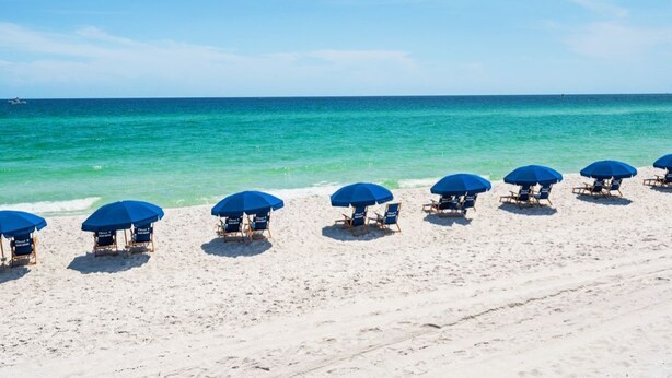A beach with rows of blue umbrellas and lounge chairs facing the ocean. - Destin, FL Spacious 3BR Condo,  Family Friendly  (Destin)