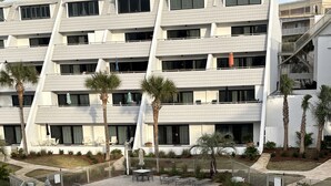 A modern hotel with a swimming pool, outdoor seating, and palm trees. - Destin, FL Spacious 3BR Condo,  Family Friendly  (Destin)