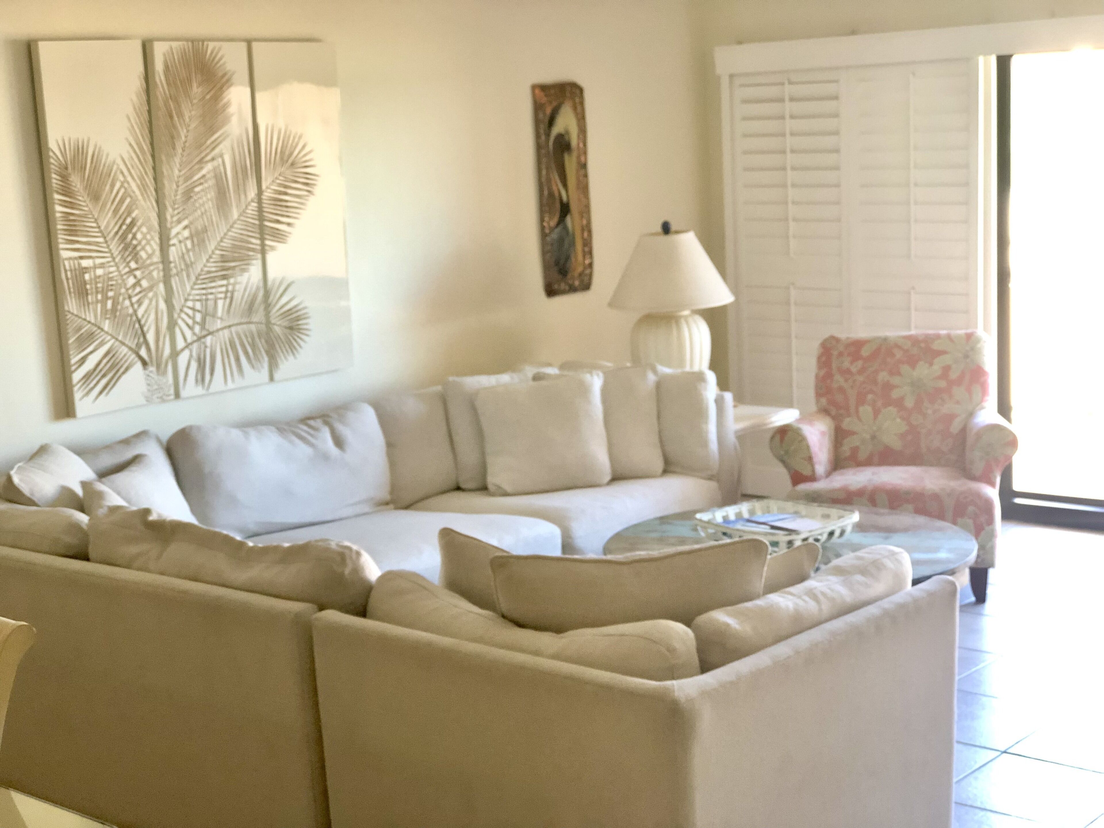 A living room with a beige sofa, a floral armchair, a side table, and a lamp.