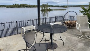 Une terrasse avec une table ronde et des chaises, un drapeau et une vue sur un lac.