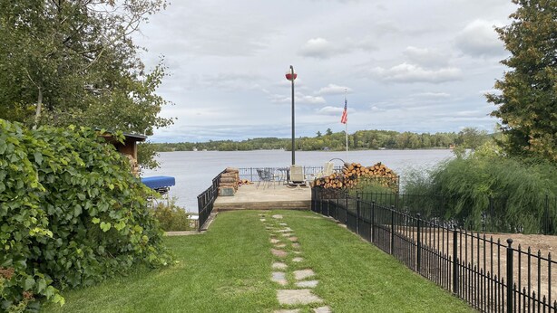 Un sentier mène à une terrasse au bord du lac, d’où l’on a une vue sur le lac, ainsi qu’un drapeau et une pile de bois de chauffage.