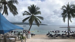 Un espace aménagé au bord de la plage, avec des parasols, des chaises longues et une vue sur la mer.
