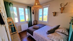 A bedroom with a bed, a wooden ladder, a hanging light fixture, and a view of the sea through a window. - Villa Ti Ann 4 persons, sea view. stand 50 meters (Cleder)