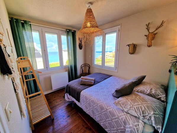 A bedroom with a bed, a wooden ladder, a hanging light fixture, and a view of the sea through a window. - Villa Ti Ann 4 persons, sea view. stand 50 meters (Cleder)