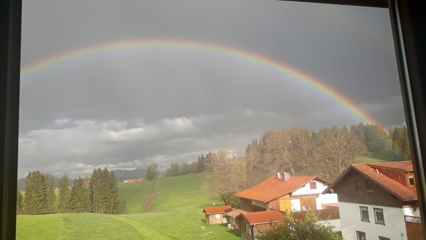 A rural landscape with houses, a rainbow, and a cloudy sky. - Ihr Ferienhof am Rande der Alpen (Seeg)