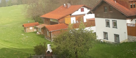 Una casa con techo rojo, un trampolín y un césped verde.