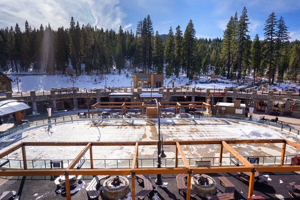 A snow-covered outdoor area with a children's ski and snowboard school, a restaurant, and a view of a forested mountain.