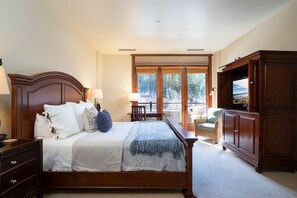 A bedroom with a large bed, wooden headboard, and a television cabinet.