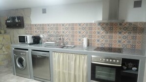 Een functionele keuken met een wasmachine, magnetron en oven.