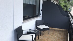 A balcony with two wicker chairs and a small table, a window with curtains, and a tiled floor. - Quite double rooms with breakfast (Hornberg)
