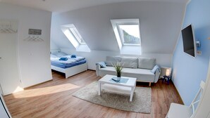 Een moderne woonkamer met een bank, een salontafel en een bed met dakraam.