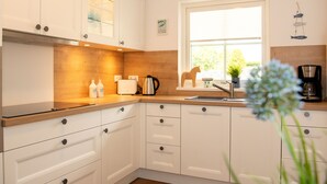 Een moderne keuken met witte kasten, een houten aanrecht, een spoelbak en een raam.