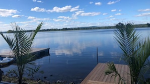 A calm lake with a wooden dock and a small boat. - Glamping at the Cabana! (Wendover, On)