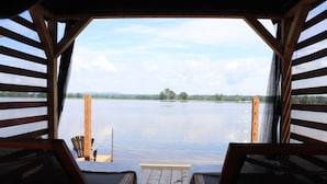 A wooden deck with two lounge chairs facing a calm lake. - Glamping at the Cabana! (Wendover, On)