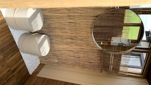 A room with a wooden floor, a circular mirror, and two cylindrical objects on the floor. - Glamping at the Cabana! (Wendover, On)