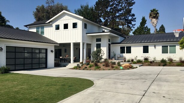 Ein zweistöckiges Haus mit überdachter Veranda, Garage und einem Basketballkorb im Garten.